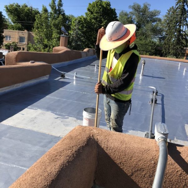 Roof worker in a hat working on a roof in daylight.